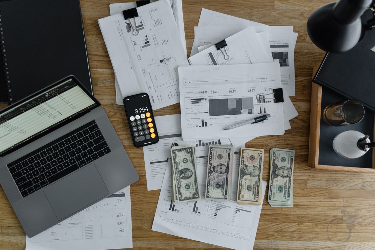 Desk with laptop, financial charts and cash representing economic opportunities